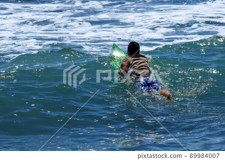 A surfer rowing offshore in search of good waves in the sea of Inamuragasaki, Kamakura, Shonan Beach 89984007