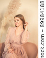 girl in pastel-colored dress sits on chair and looks away 89984188