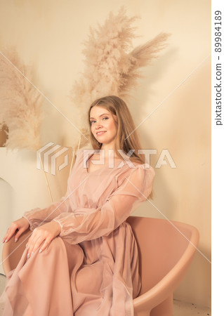 girl in pastel-colored dress sits on chair and looks away 89984189