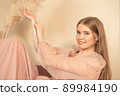 girl in pastel-colored dress sits on chair with her legs up 89984190