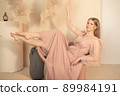 girl in pastel-colored dress sits on chair with her legs up 89984191