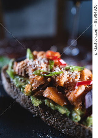 person eats fresh sandwich with avocado, red salmon fried fish, seaweed, pepper 89984920