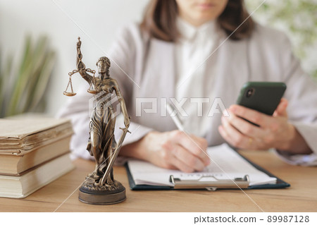 lawyer woman in a light jacket works in an office, a statuette of themis, the goddess of justice 89987128