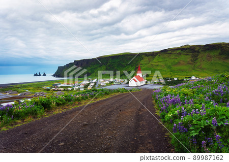 Dirt road going to the village of Vik and its lutheran church in Iceland Dirt road going to the village of Vik and its lutheran church in Iceland 89987162