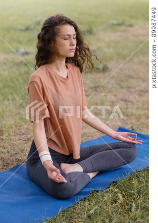 woman with curly hair meditates in a park. yoga and meditation for mental and physical health 89987449