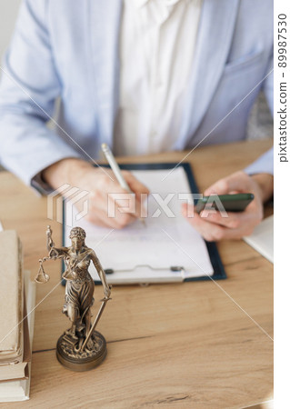 male lawyer in a white shirt and jacket works in the office, a statuette of the goddess of justice Themis on the table male lawyer in a white shirt and jacket works in the office, a statuette of the goddess of justice Themis on the table 89987530