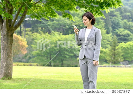 Woman holding a smartphone outdoors Woman holding a smartphone outdoors 89987877