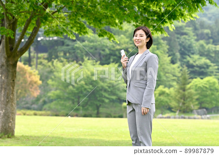 Woman holding a smartphone outdoors Woman holding a smartphone outdoors 89987879