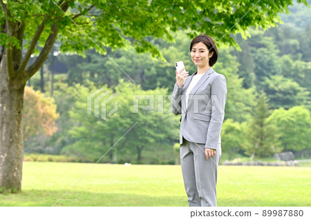 Woman holding a smartphone outdoors Woman holding a smartphone outdoors 89987880