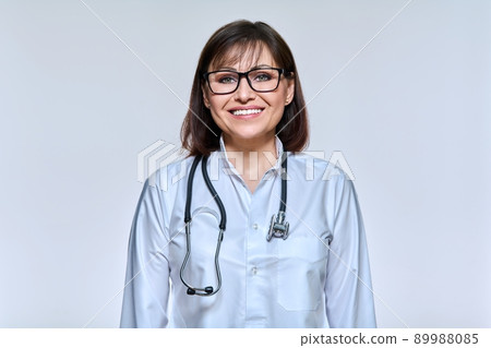 Portrait of mature woman doctor with stethoscope on light studio background Portrait of mature woman doctor with stethoscope on light studio background 89988085