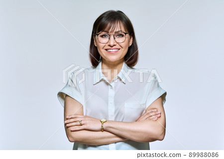 Portrait of positive confident middle aged woman looking at camera, on light background Portrait of positive confident middle aged woman looking at camera, on light background 89988086