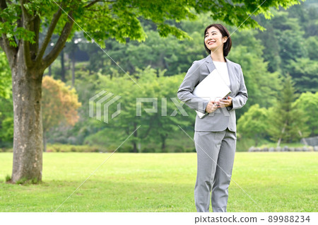 Woman in a business suit holding a computer outdoors 89988234