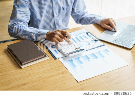 Close up hands of business man using a calculator to calculate expenses from receipts placed on the table. tax concept. 89988625