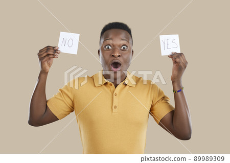 Funny confused young man holding YES and NO sticky notes and trying to make a choice Funny confused young man holding YES and NO sticky notes and trying to make a choice 89989309