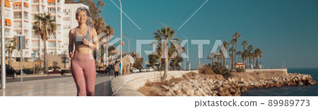 Sporty athletic lady actively running by the waterfront Sporty athletic lady actively running by the waterfront 89989773