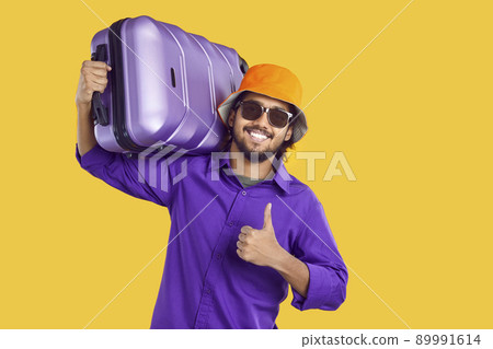 Happy Indian man going on holiday trip, carrying suitcase, smiling and giving thumbs up Happy Indian man going on holiday trip, carrying suitcase, smiling and giving thumbs up 89991614