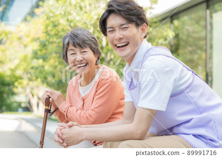 Senior woman sitting with a cane and a young male nurse shooting cooperation "LINK FOREST" 89991716