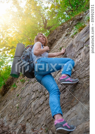 A young woman is engaged in rock climbing. Leisure and active sports. Light. Bottom view 89992031