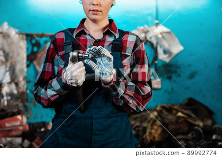 Young female mechanic in uniform and gloves, holding a tool. Close-up of the employee's hands 89992774