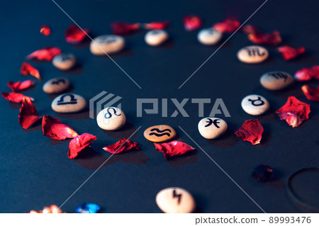 Astrology and horoscope. Stones with the signs of the zodiac, laid out in a circle, decorated with rose petals. The concept of divination and magic Astrology and horoscope. Stones with the signs of the zodiac, laid out in a circle, decorated with rose petals. The concept of divination and magic 89993476