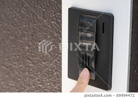 Finger pressing the button on the intercom Finger pressing the button on the intercom 89994472