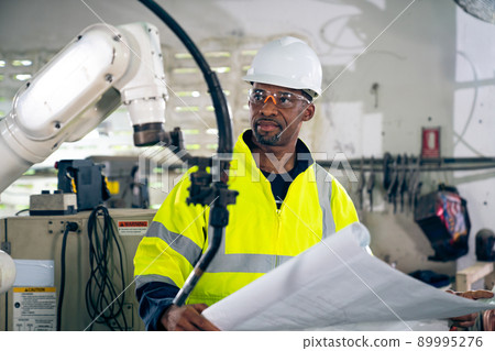 African American factory worker working with adept robotic arm 89995276