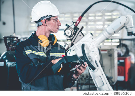 Young factory worker working with adept robotic arm 89995303