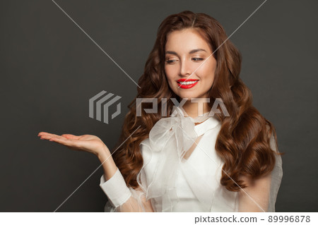 Happy woman holding open hand and smiling on black background 89996878