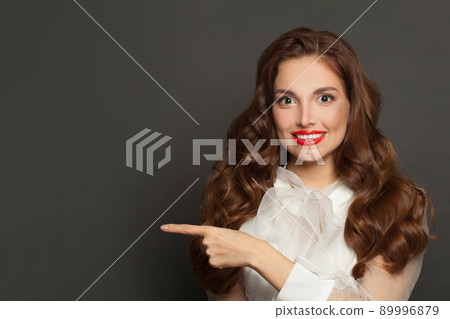 Perfect successful woman fashion model smiling and pointing aside on gray studio background 89996879