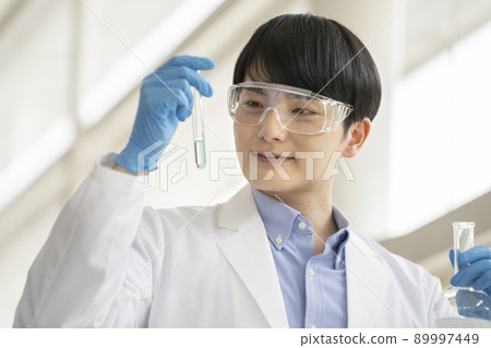一個穿著實驗室外套的年輕人在做實驗 一個穿著實驗室外套的年輕人在做實驗 89997449