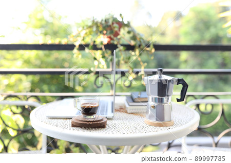 Coffee glass cup and moka pot and laptop on metal table Coffee glass cup and moka pot and laptop on metal table 89997785