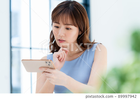 A woman watching a video on a smartphone A woman watching a video on a smartphone 89997942