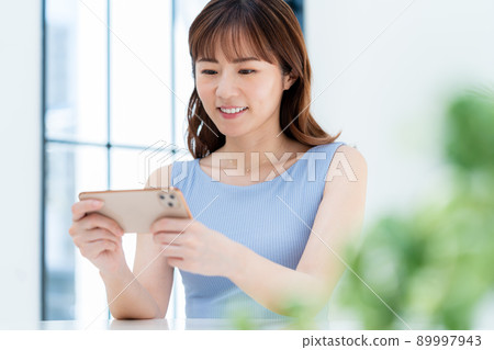 A woman watching a video on a smartphone A woman watching a video on a smartphone 89997943