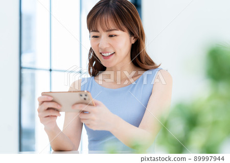 A woman watching a video on a smartphone A woman watching a video on a smartphone 89997944