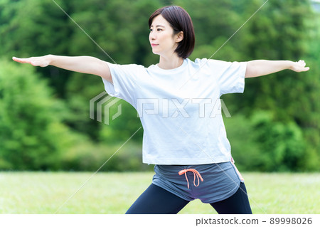 Young woman doing yoga in the fresh green 89998026