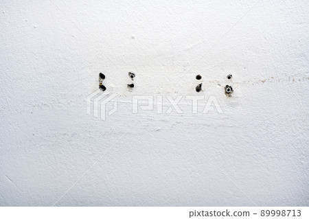 Hole and dowels in an old dirty white wall. 89998713