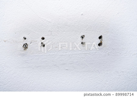 Hole and dowels in an old dirty white wall. 89998714
