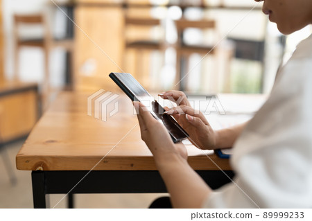 Closeup image of a beautiful young asian woman holding and using mobile phone 89999233