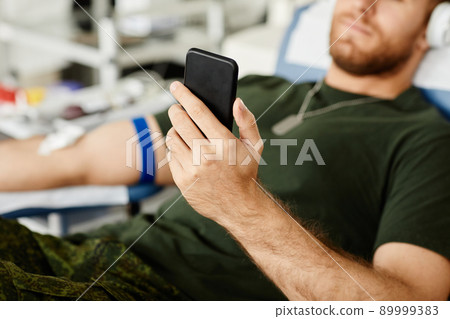 Blood Donor using Smartphone Closeup 89999383