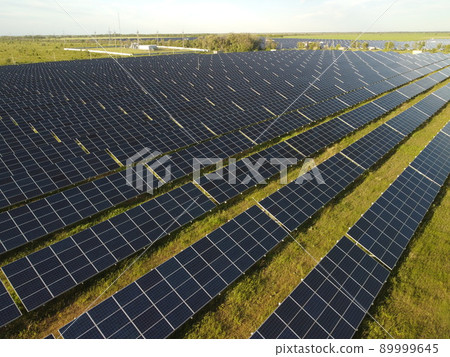 Aerial top view of a solar panels power plant. Photovoltaic solar panels at sunrise and sunset in countryside from above. Modern technology, climate care, earth saving, renewable energy concept. 89999645