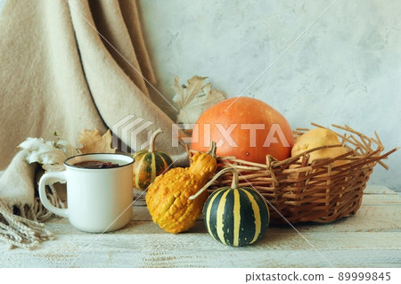 Cup of tea, dry fruits, cashmere plaid, pumpkins and autumn leaves in a basket of leaves, on a wooden table, home comfort concept, Thanksgiving Cup of tea, dry fruits, cashmere plaid, pumpkins and autumn leaves in a basket of leaves, on a wooden table, home comfort concept, Thanksgiving 89999845