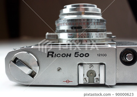 Ricoh 500 silver camera with lens pointed up against a white and gray background 90000623
