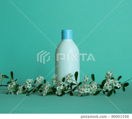 A bottle for cosmetic products without a label with a flower branch at the bottom. Facial skin care concept. 90001598