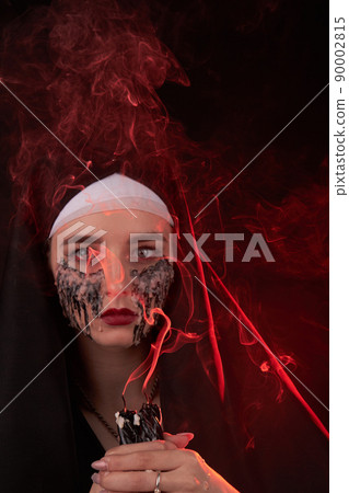 Portrait of a young girl with extinguished candles for satanic ritual . 90002815