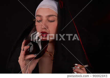 Bad girl wearing catholic hood and drinking red wine . Bad girl wearing catholic hood and drinking red wine . 90002843