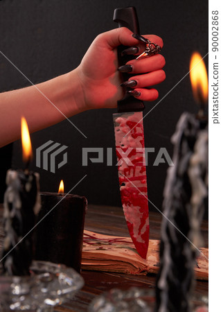 Vertical shot of female hand stabbing the knife into the bible book. Vertical shot of female hand stabbing the knife into the bible book. 90002868