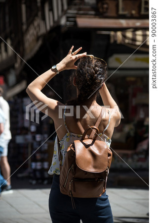 Portrait on back view of young woman taking a photo with her smartphone Portrait on back view of young woman taking a photo with her smartphone 90003867