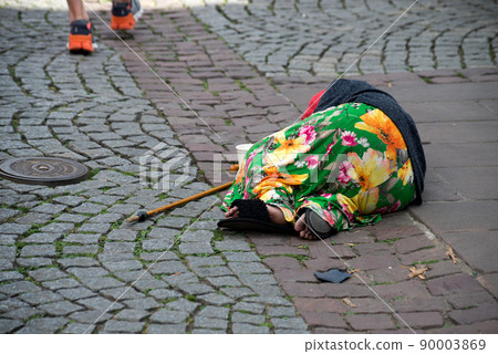 Portrait on back view of homeless romanian woman lying in the street 90003869