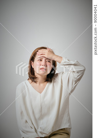 A young woman who catches a cold and puts her hand on her forehead 90004041