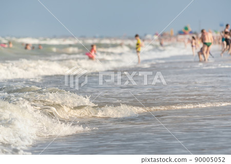 Scenic view sand shore of sea or ocean waves on sunny beach of summer resort crowded with many people relaxing on hot day. Tourism vacation concept 90005052
